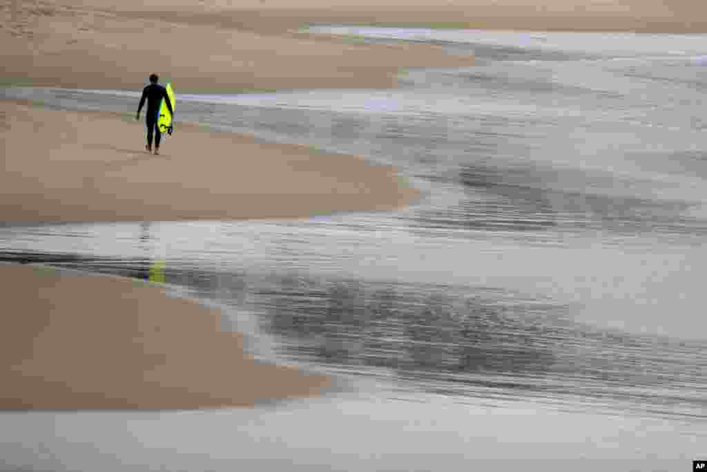 A surfer is seen walking along Bronte Beach in Sydney, Australia.