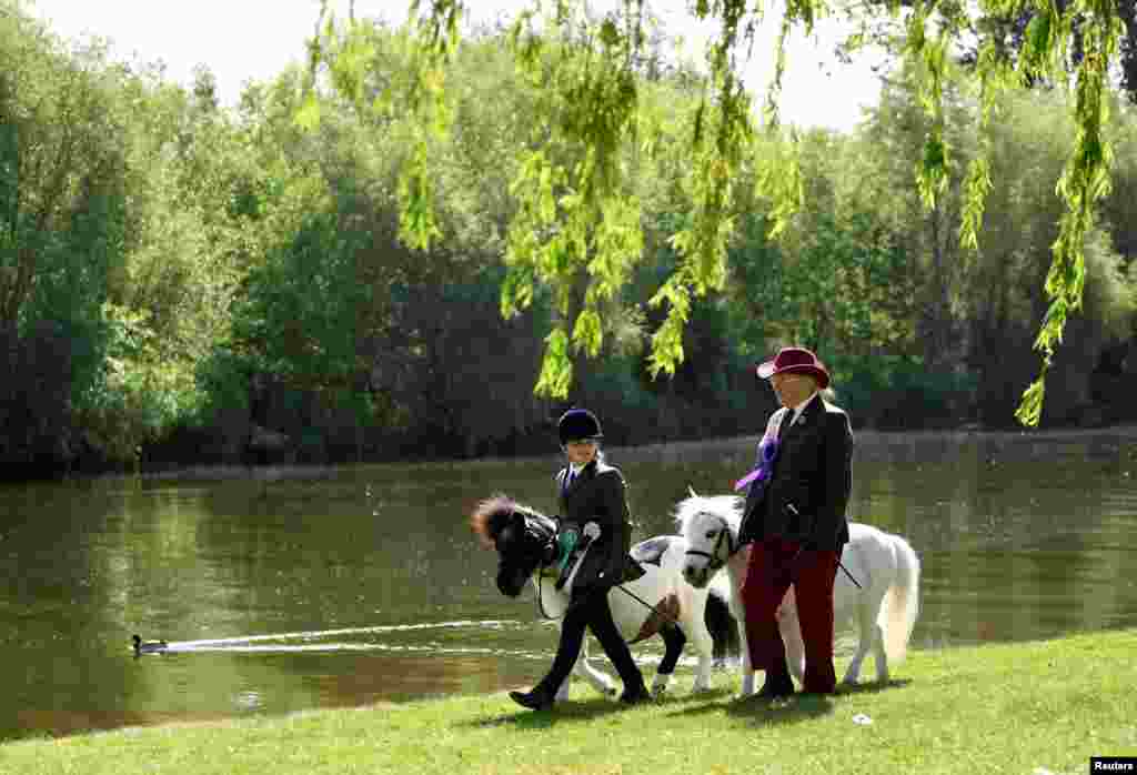 Participant Olivia Locking, 11, walks her horse, Lucky, together with June Trotter and her horse, Merry Legs, beside the River Thames after competing on day one of the Royal Windsor Horse Show in Windsor, Britain.