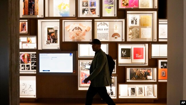A man walks past a portion of the archive wall at the Bob Dylan Center, May 5, 2022, in Tulsa, Okla.