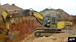 FILE - In this photograph taken on April 4, 2018, a Chinese employee of a mining company operates a machine at a mining site in the Cameroon town of Betare Oya.