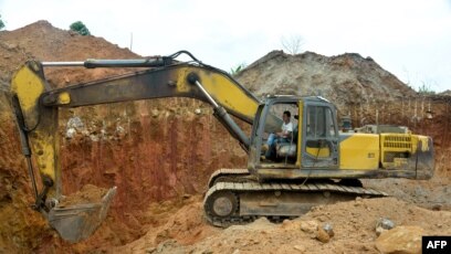 FILE - In this photograph taken on April 4, 2018, a Chinese employee of a mining company operates a machine at a mining site in the Cameroon town of Betare Oya.