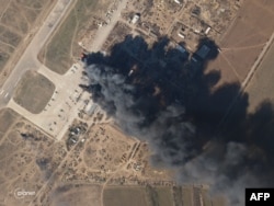 FILE - This Planet Labs satellite image taken on March 15, 2022, shows Kherson air base on fire after an alleged airstrike against Russian forces occupying the base.