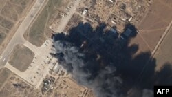 FILE - This Planet Labs satellite image taken on March 15, 2022, shows Kherson air base on fire after an alleged airstrike against Russian forces occupying the base. 
