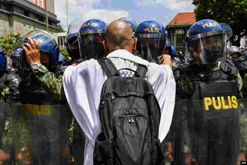 A Catholic priest tries to speak to police during a rally in front of the commission on elections in Manila, to protest results of the May 9 presidential election.