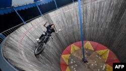FILE - Daredevil Karmila Purba, a rider of the "wall of death" performing inside a six-meter-high wall at a night carnival in Bogor, Indonesia, April 30, 2022.