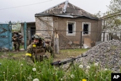 Det ukrainska nationalgardet patrullerar under ett spaningsuppdrag i en nyligen återtagen by i utkanten av Charkiv, östra Ukraina, 14 maj 2022.