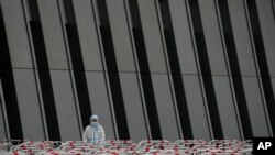 A worker in a protective suit stands watch near the barricades set up for COVID-19 tests at a testing site after authorities ordered a third round of three consecutive coronavirus tests for residents in the Chaoyang district on May 8, 2022, in Beijing.