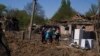 People react as they stand next to a crater in destroyed residential area after Russian airstrike in Bakhmut, Donetsk region, Ukraine, May 7, 2022. 