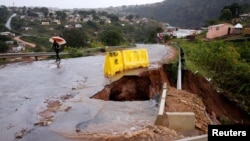 Water from heavy rains runs along a road, which was damaged during previous flooding, in kwaNdengezi near Durban, South Africa, May 22, 2022. 