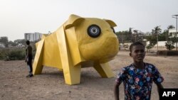 Un garçon marche devant une installation artistique de l'artiste égyptien Khaled Zaki, le long de la promenade maritime de Dakar, le 11 mai 2022.