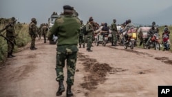 FILE - People walk along a road near Kibumba, north of Goma, Democratic Republic of Congo, as they flee fighting between Congolese forces and M23 rebels in North Kivu, May 24, 2022. 