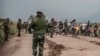 Sejumlah pasukan Kongo tampak berada di jalan di dekat Kibumba, Republik Demokratik Kongo, pada 24 Mei 2022. Mereka mengawasi para warga yang pergi melarikan diri dari rumahnya di Kivu Utara setelah terjadi bentrokan antara pasukan Kongo dan pemberontak M23. (Foto: AP)