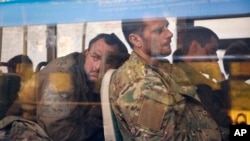 Ukrainian servicemen sit in a bus after they were evacuated from the besieged Mariupol Azovstal steel plant, near a remand prison in Olyonivka, in territory under the government of the Donetsk People's Republic, eastern Ukraine, May 17, 2022.