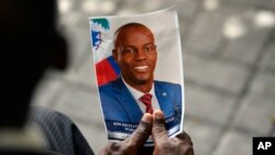 FILE - A person holds a photo of late Haitian President Jovenel Moise during his memorial ceremony at the National Pantheon Museum in Port-au-Prince, Haiti, July 20, 2021.