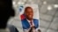 Seorang warga tampak memegang foto mantan Presiden Haiti Jovenel Moise dalam upacara pemakamannya di National Pantheon Museum, Port-au-Prince, Haiti, pada 20 Juli 2021. (Foto: AP/Matias Delacroix)