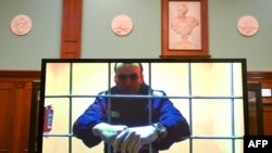 FILE - Alexey Navalny appears on a screen set up at a courtroom of the Moscow City Court via a video link from his prison colony during a hearing of an appeal against his nine-year prison sentence, May 17, 2022.