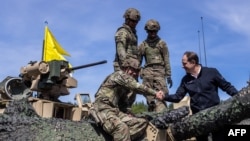 U.S. Ambassador to Poland Mark Brzezinski shakes hands with U.S. soldiers on a tank as troops from Poland, United States, France and Sweden take part in the DEFENDER-Europe 22 military exercise, in Poland, May 19, 2022.