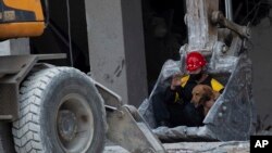 Un rescatista y su perro de búsqueda son transportados en la pala de una excavadora para buscar sobrevivientes en el lugar de una explosión mortal dos días antes que destruyó el Hotel Saratoga de cinco estrellas en La Habana Vieja, Cuba, el 8 de mayo de 2022.