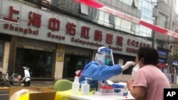 FILE - A medical worker conducts COVID-19 tests for residents after a confirmed case was found in the community on April 10, 2022, in Shanghai.