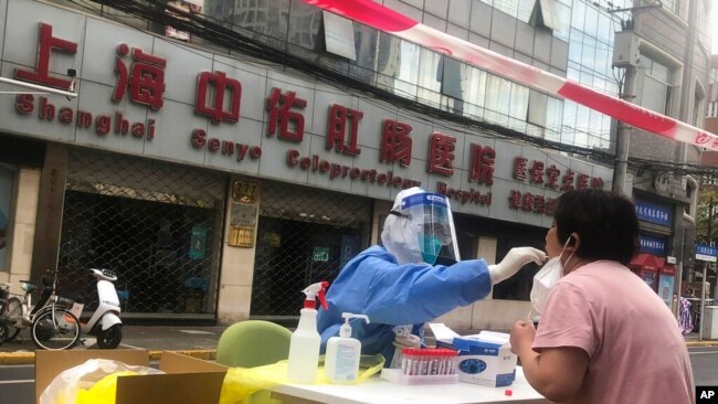 FILE - A medical worker conducts COVID-19 tests for residents after a confirmed case was found in the community on April 10, 2022, in Shanghai.