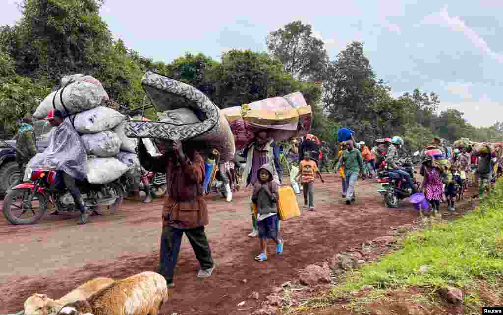 Congolese civilians carry their belongings as they flee near the Congolese border with Rwanda after fightings broke out in Kibumba, outside Goma in the North Kivu province of the Democratic Republic of Congo, May 24, 2022.