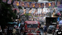 A passenger jeepney passes campaign posters outside a polling center in Manila, Philippines, May 6, 2022. 