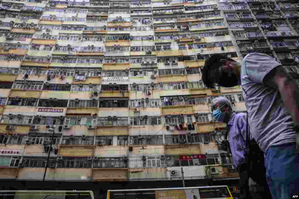 People walk past a residential apartment block in Hong Kong.