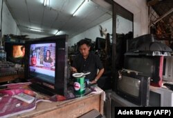 Seorang pria memperbaiki pesawat televisi di bengkelnya di Jakarta pada 21 Maret 2022. (Foto: AFP/Adek Berry)