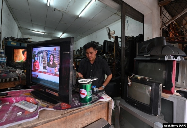 Seorang pria memperbaiki pesawat televisi di bengkelnya di Jakarta pada 21 Maret 2022. (Foto: AFP/Adek Berry)