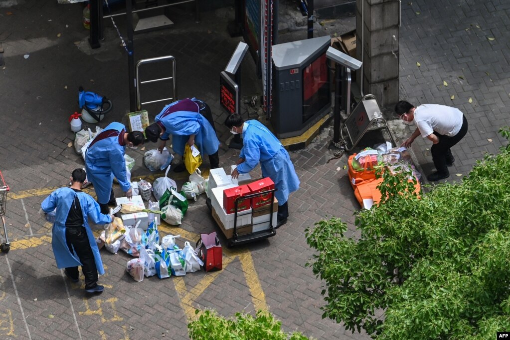 身穿防护服的人员在上海静安区给封在小区里的居民发放食物。（2022年5月8日）(photo:VOA)