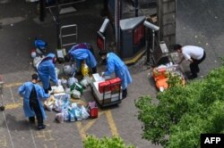 身穿防护服的人员在上海静安区给封在小区里的居民发放食物。（2022年5月8日）