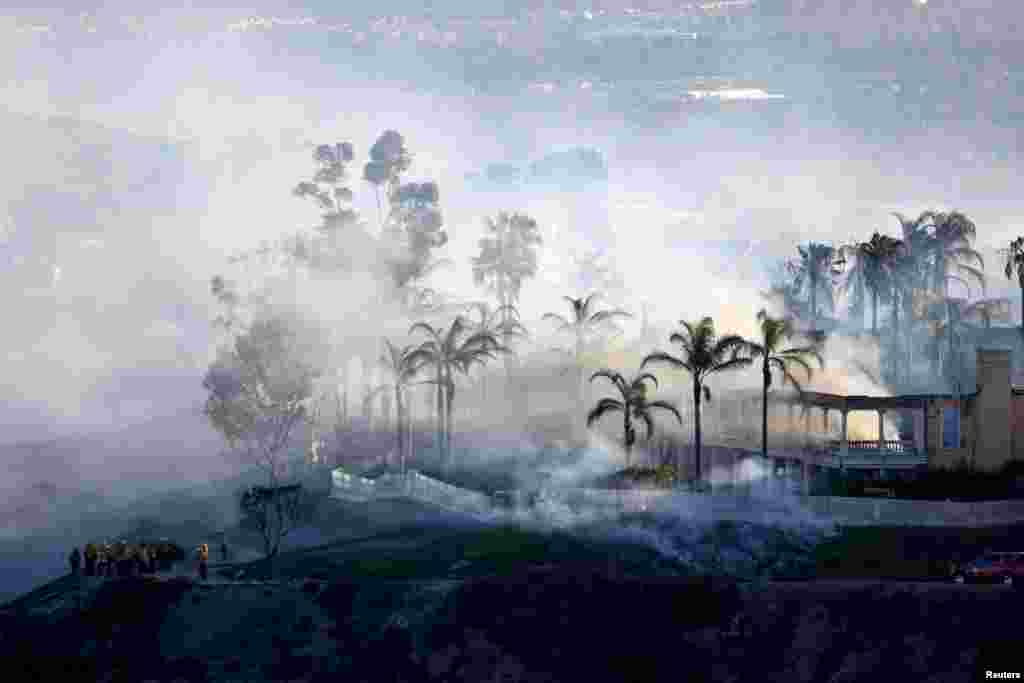 Smoke from a fast-moving, wind-driven wildfire rises above a neighborhood in Laguna Niguel, California.