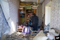 Las mujeres recogen sus pertenencias en su apartamento destruido por el ataque aéreo ruso en Bakhmut, región de Donetsk, Ucrania, el sábado 7 de mayo de 2022. (Foto AP/Evgeniy Maloletka)