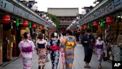 FILE - Tourists in traditional Japanese kimonos walk in Asakusa district in Tokyo, July 27, 2020. 