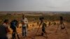 FILE - TV reporters work on a hilltop on the Turkey-Syria border overlooking Ras al-Ayn in northeastern Syria, Oct. 20, 2019. Journalists in northeastern Syria now face a requirement to join an official union before being credentialed.