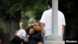 Seorang ayah menenangkan putrinya yang histeris, di lokasi di mana para siswa dievakuasi dari Sekolah Dasar "Robb" pasca penembakan yang menewaskan 19 siswa dan 2 orang guru di kota Uvalde, Texas, AS (24/5). (Foto: Reuters)