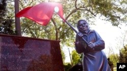 FILE - Sculpture of Ukrainian woman holding a Soviet-era red flag is seen during celebration of the 77th anniversary of the end of World War II in Mariupol, in territory under the government of the Donetsk People's Republic, eastern Ukraine, May 9, 2022.