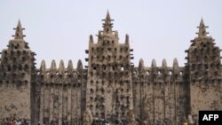 FILE - People take part in the annual rendering of the Great Mosque of Djenne in central Mali on April 28, 2019.