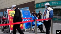 FILE - Residents line up for COVID tests, May 12, 2022, in Beijing. China's leaders are struggling to reverse an economic slump without giving up anti-virus tactics that shut down Shanghai and other cities.