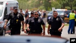 Police officers walk near Robb Elementary School following a mass shooting in Uvalde, Texas, May 24, 2022.