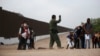 A Border Patrol agent instructs migrants who had crossed the Rio Grande river into the U.S. in Eagle Pass, Texas, Friday, May 20, 2022. 