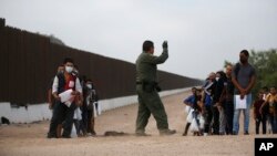 A Border Patrol agent instructs migrants who had crossed the Rio Grande river into the U.S. in Eagle Pass, Texas, Friday, May 20, 2022. 