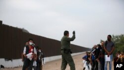 Agentes de la Patrulla Fronteriza de EEUU dan instrucciones a migrantes que cruzaron el Río Grande hacia territorio estadounidense en el estado de Texas, el 20 de mayo de 2022.
