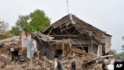 Men walk past a damaged building after Russian shelling in Soledar, Donetsk region, Ukraine, Wednesday, May 18, 2022. (AP Photo)