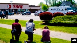 FILE - People pray outside the scene of a shooting at a supermarket, in Buffalo, NY, May 15, 2022.