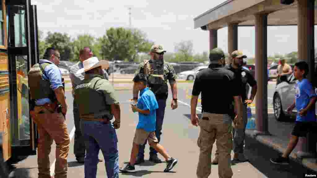 Children get on a school bus as law enforcement personnel guard the scene near Robb Elementary School in Uvalde, Texas, May 24, 2022.