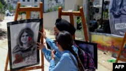 Two girls attend at an art exhibit honoring the late Palestinian Al Jazeera journalist Shireen Abu Akleh in Jenin city in the occupied West Bank, May 19, 2022.