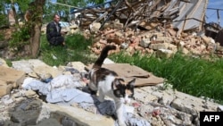 A local resident sits at a destroyed house in Vilkhivka village, near Kharkiv, on May 25, 2022, amid Russia's invasion of Ukraine.