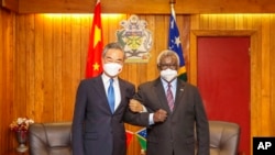 根据新华社发布的照片，2022年5月26日，所罗门群岛总理索加瓦雷在霍尼亚拉与来访的中国外交部长王毅握手。（美联社）