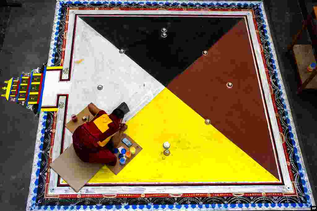 A Tibetan Buddhist monk living in exile creates a traditional design on the floor in preparation for prayers in Dharmsala, India.